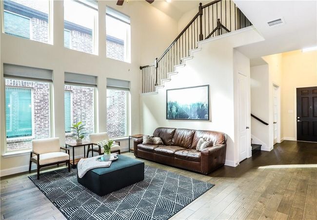 Living area with stairs, wood finished floors, a towering ceiling, plenty of natural light, and ceiling fan | Image 9