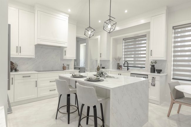Kitchen featuring white cabinets, a center island, decorative backsplash, a sink, and a breakfast bar area | Image 9