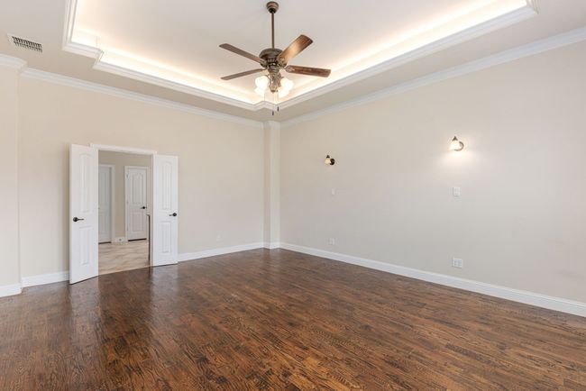 Spare room with visible vents, a ceiling fan, wood finished floors, crown molding, and a raised ceiling | Image 24