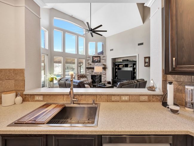 Kitchen sink image featuring a view to the open family room, a stone fireplace, and a ceiling fan | Image 16