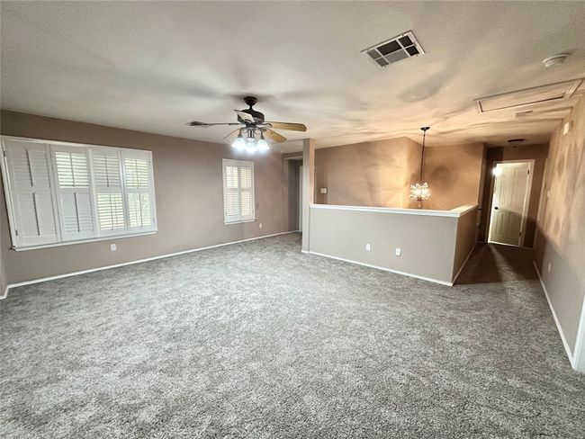 Carpeted empty room featuring attic access, ceiling fan, and a smoke detector | Image 11