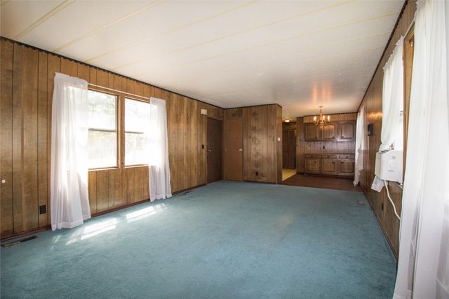 Empty room featuring a chandelier, wood walls, and carpet | Image 10