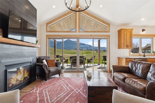 Living area featuring a glass covered fireplace, a mountain view, recessed lighting, lofted ceiling, and wood finished floors | Image 23