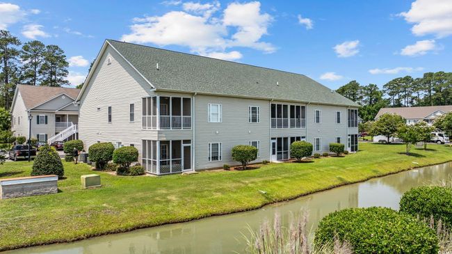 Back of house featuring a sunroom, a water view, roof with shingles, and a lawn | Image 23