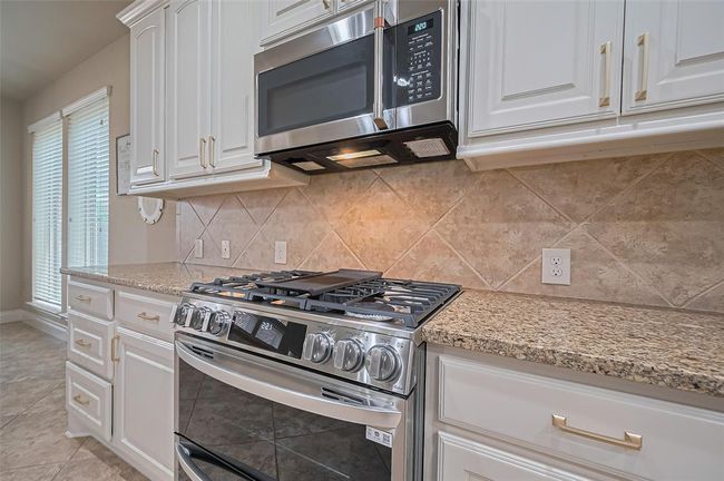 Featuring a stainless steel gas range with double ovens and an overhead built-in microwave, the kitchen is designed for both everyday meals and special gatherings. | Image 11