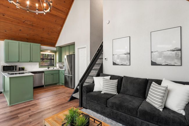Living room with high vaulted ceiling, stairway, a chandelier, light wood-type flooring, and wood ceiling | Image 21