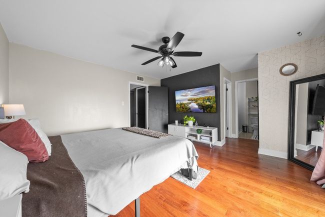 Primary Bedroom featuring a ceiling fan, wood-style flooring with en-suite bathroom, a spacious walk-in closet and access to the balcony with a view to the pool | Image 27
