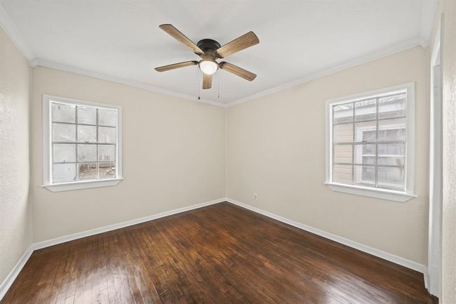 Bright and airy secondary bedroom with neutral paint, vinyl plank floors, crown molding, a ceiling fan and windows providing views to your backyard. | Image 14
