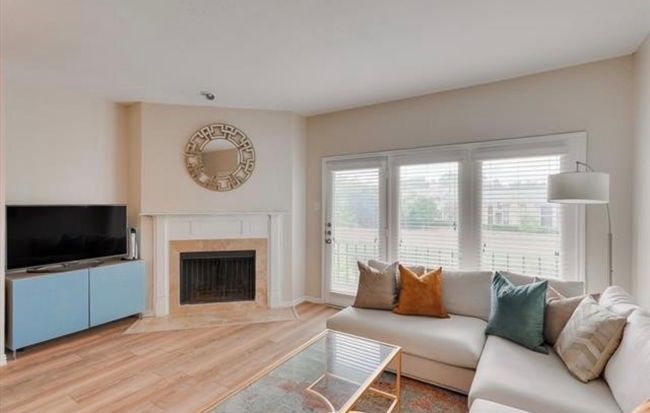 Living area featuring wood finished floors, plenty of natural light, and a fireplace | Image 11