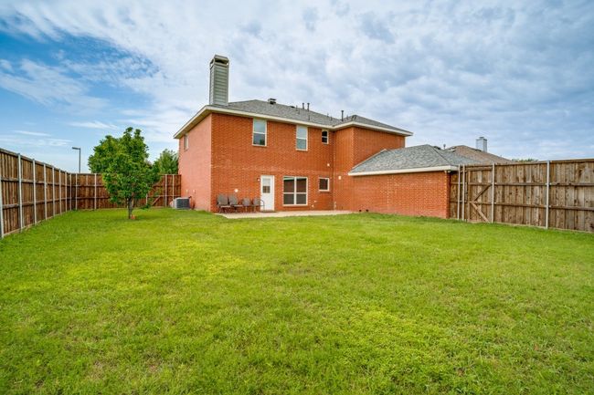 Back of property with brick siding, central air condition unit, a chimney, and a patio area | Image 34