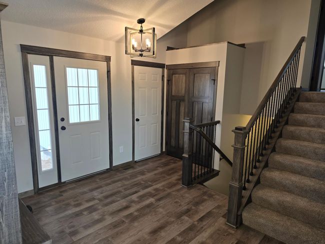 Nice luxurious vinyl plank flooring in the entrance area. Wood/Iron railing system on the stairway going up and down. | Image 10