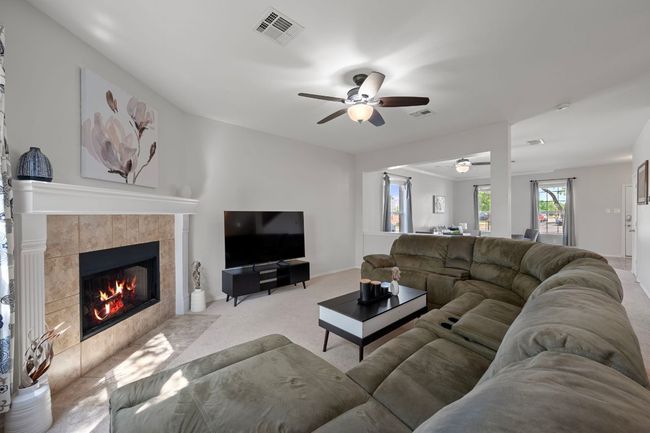 Carpeted living area with a ceiling fan and a tile fireplace | Image 8