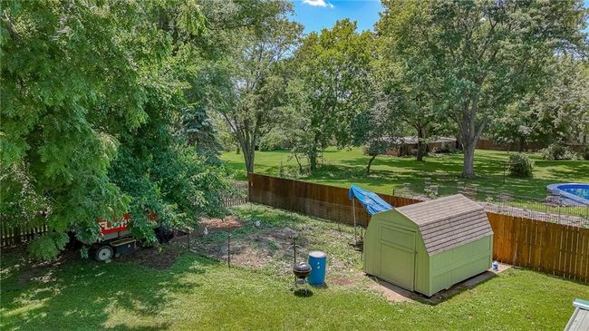 Fenced backyard with a storage unit and view of scattered trees | Image 43