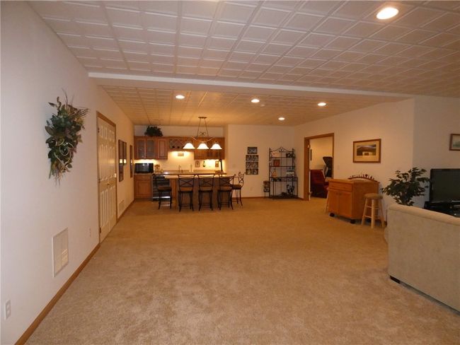 This lower-level area offers an acoustic ceiling, wet bar with refrigerator and a 5-seat island w/quartz countertop | Image 40