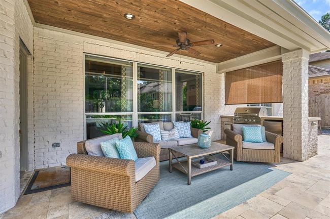 Covered porch with seating and summer kitchen. Summer kitchen complete with gas grill, refrigerator and builtin trash bin. Custom poured concrete countertop. | Image 41