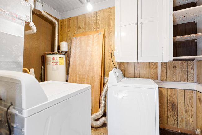 Washroom featuring separate washer and dryer, wood walls, cabinet space, and gas water heater | Image 17