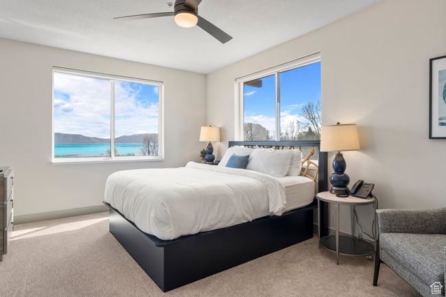 Bedroom with carpet floors, multiple windows, ceiling fan, and a water view | Image 51