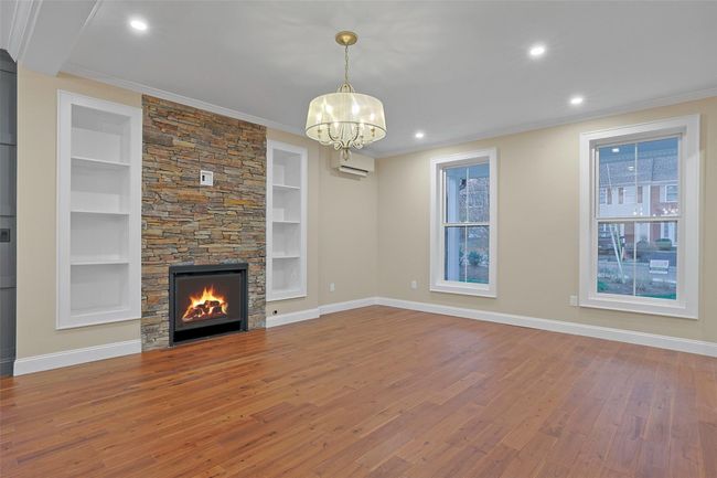 Living room features a natural gas fireplace, with stacked stone surround, flanked by built in bookcases. | Image 8