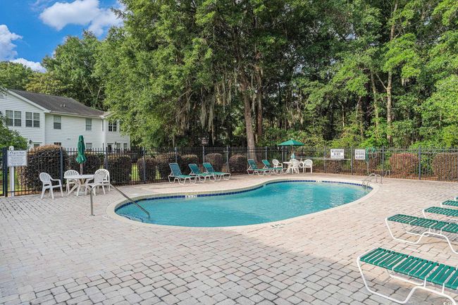 Community pool featuring a patio and view of wooded area | Image 12