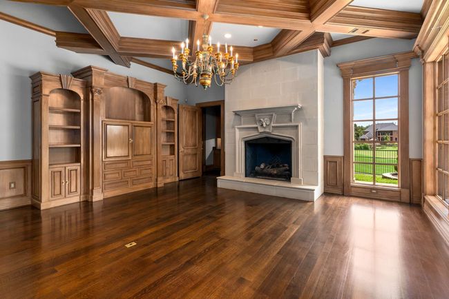 Unfurnished living room featuring coffered ceiling, a chandelier, dark wood finished floors, beamed ceiling, and a high end fireplace | Image 25