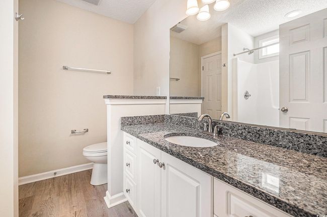 Full bath with vanity, a textured ceiling, wood finished floors, and a shower | Image 23