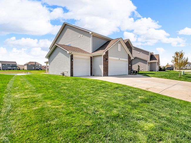 exterior space with concrete driveway, a shingled roof, a front lawn, brick siding, and a 3 car garage | Image 40