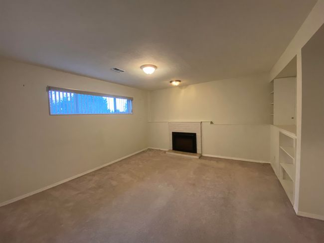 Unfurnished living room with carpet flooring, visible vents, a fireplace, and baseboards | Image 13
