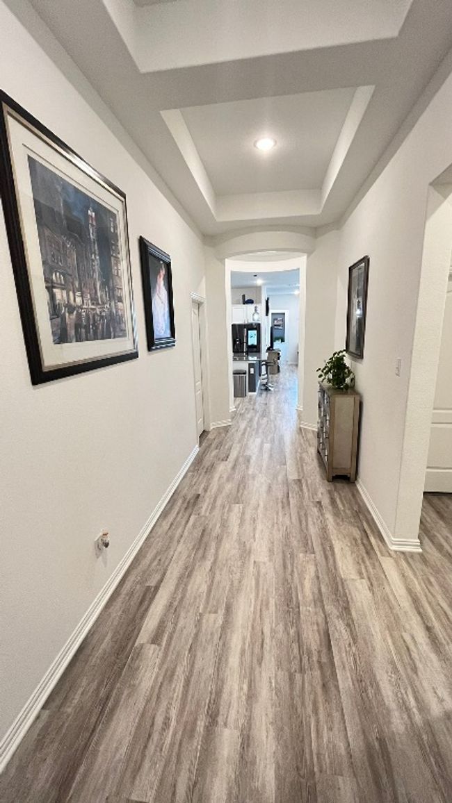 Hallway featuring a raised ceiling, wood finished floors, baseboards, and arched walkways | Image 6
