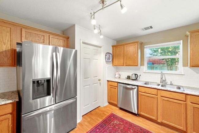Kitchen featuring stainless steel appliances, a sink, light wood-style floors, and tasteful backsplash | Image 16