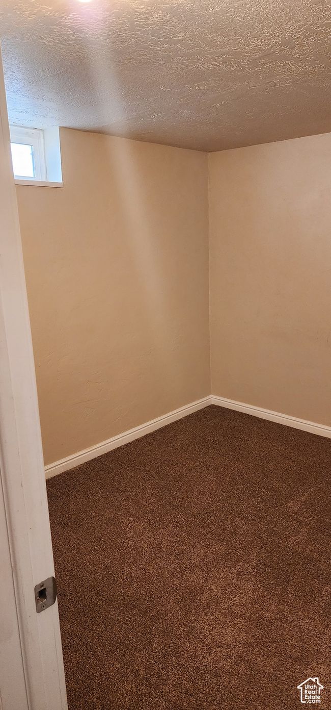Spare room featuring dark colored carpet, a textured ceiling, and baseboards | Image 23