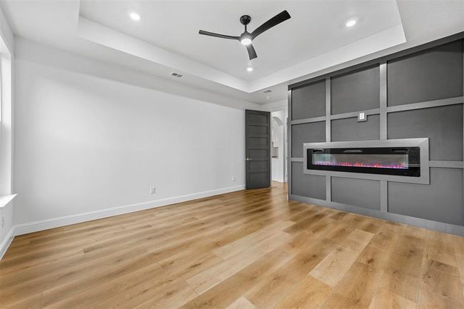 Unfurnished living room featuring light hardwood / wood-style flooring, ceiling fan, and a tray ceiling | Image 26