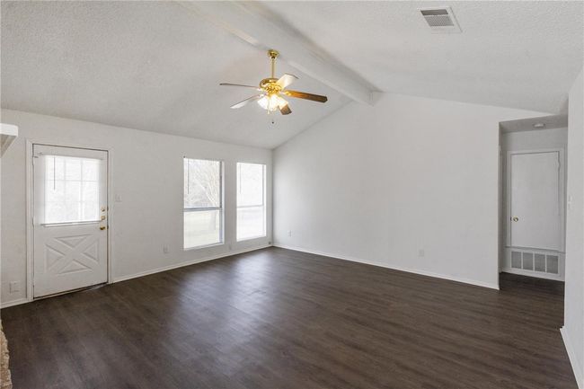 Living Room with vaulted ceiling and and fan. Door on the left leads to the large backyard. Door to the right leads to the primary bedroom and the converted garage area. | Image 10