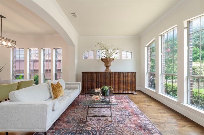 Living area with plenty of natural light, ornamental molding, wood finished floors, and arched walkways | Image 7