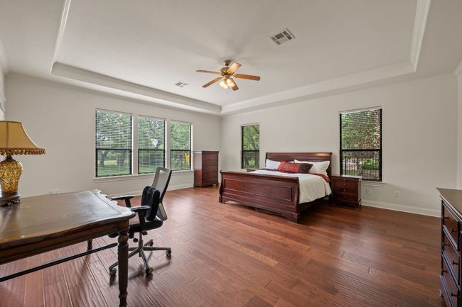 Bedroom featuring dark wood-style floors, visible vents, baseboards, and a tray ceiling | Image 20