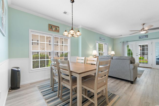 Dining room with a chandelier, light wood-style floors, ornamental molding, wainscoting, and ceiling fan | Image 9