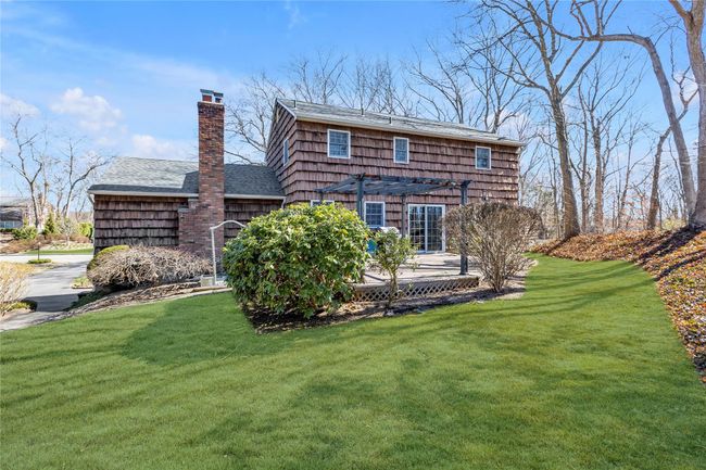 Back of house featuring a chimney, a pergola, roof with shingles, and a lawn | Image 22