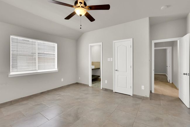 Unfurnished bedroom featuring ensuite bath, vaulted ceiling, baseboards, and ceiling fan | Image 26