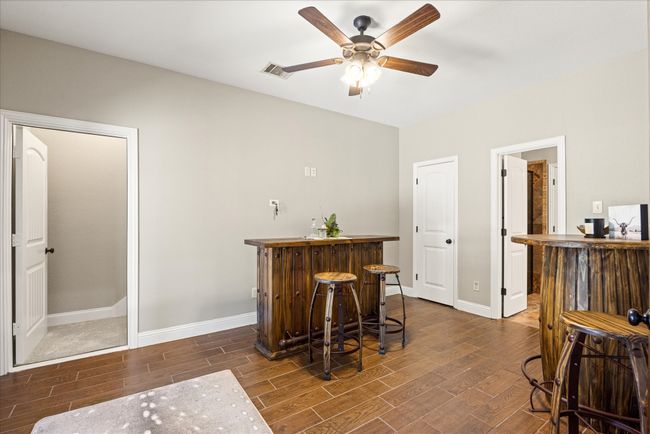 Indoor bar featuring wood finished floors and ceiling fan | Image 11