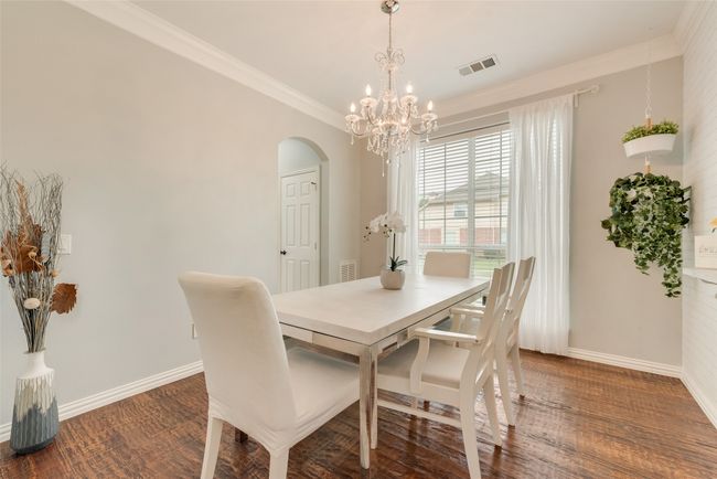 Dining area with baseboards, arched walkways, crown molding, a chandelier, and wood finished floors | Image 7