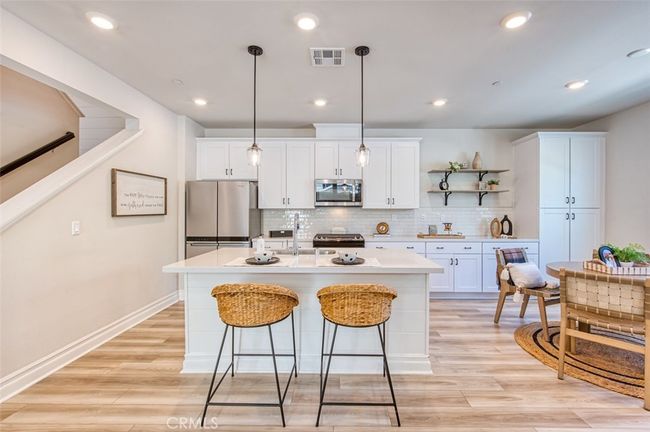 Gourmet kitchen with quartz countertops, breakfast bar island, white custom cabinetry and dining area. | Image 4