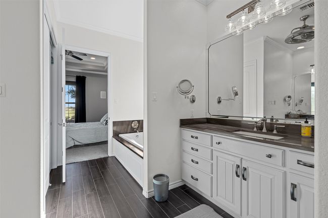 Full bathroom featuring connected bathroom, crown molding, vanity, a tub, and wood finish floors | Image 9