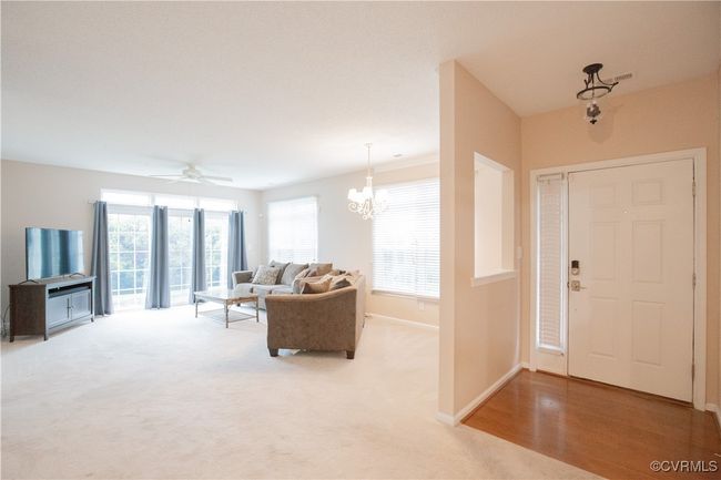 Entrance foyer featuring ceiling fan with notable chandelier, baseboards, and light colored carpet | Image 4