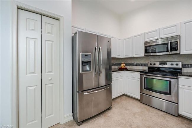 Kitchen featuring light tile patterned floors, tasteful backsplash, stainless steel appliances, and white cabinets | Image 8