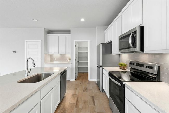 Kitchen with stainless steel appliances, light wood-style floors, tasteful backsplash, white cabinets, and recessed lighting | Image 13