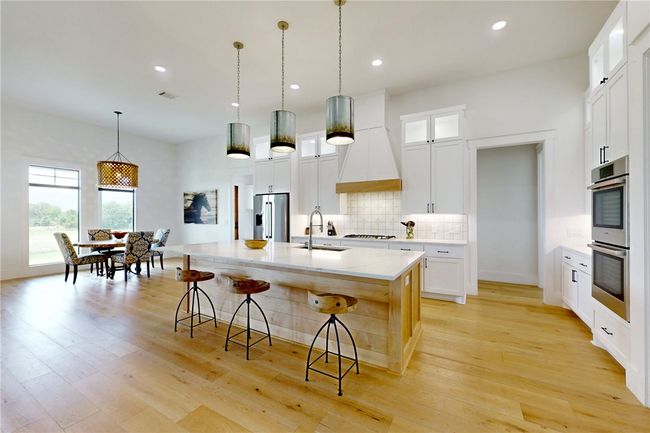 Kitchen with appliances with stainless steel finishes, a sink, tasteful backsplash, a center island with sink, and light wood-style floors | Image 9
