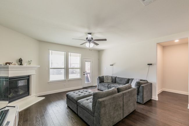 Living area featuring a glass covered fireplace, baseboards, dark wood-type flooring, and a ceiling fan | Image 22
