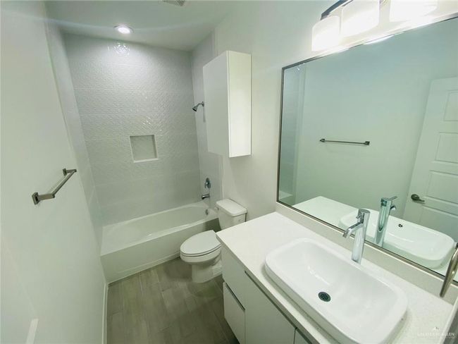 Bathroom featuring vanity, shower / washtub combination, and wood finished floors | Image 7