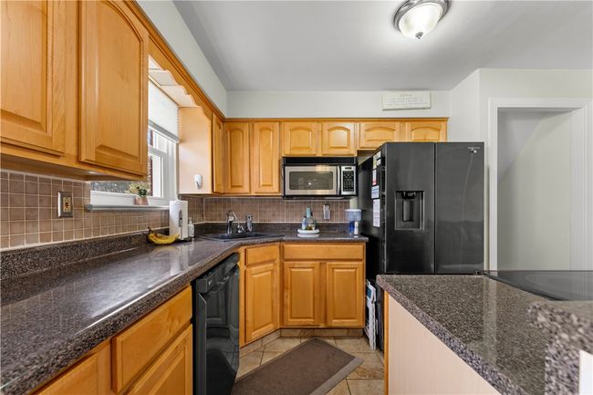 Many cabinet storage spaces, ceramic tile flooring, and a backsplash in the kitchen. | Image 8