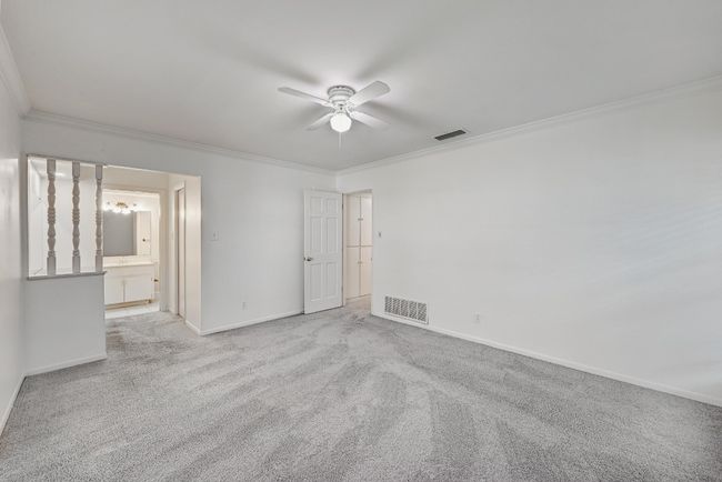 Carpeted empty room featuring crown molding, visible vents, and ceiling fan | Image 18