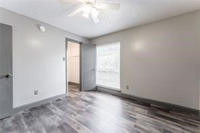 Unfurnished bedroom featuring wood finished floors, a walk in closet, a ceiling fan, a closet, and a textured ceiling | Image 16